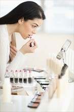 Young woman applying lipstick.