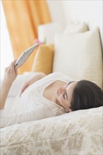Young woman lying on bed using tablet pc.