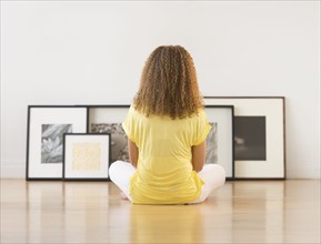 Woman sitting on floor looking at artworks.