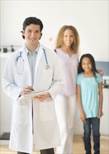 Doctor with patients (woman and girl aged 12-13) in office.