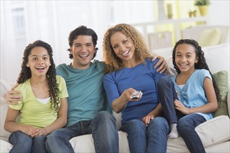 Portrait of parents with daughters (10-13) watching tv.