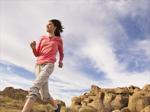 USA, California, Joshua Tree National Park, Young woman jogging in desert.