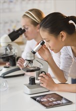 Students (14-17) in chemistry lab using microscope.