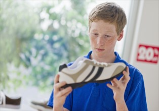 Boy (16-17) looking at shoe in shoe store.