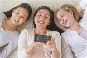 Friends (14-19) lying on floor looking at mobile phone.