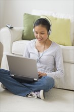 Girl (14-15) using laptop at home.