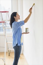Woman painting wall at home.