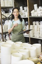 Woman with checklist in pottery warehouse.