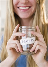 Woman holding jar with savings. 
Photo: Jamie Grill