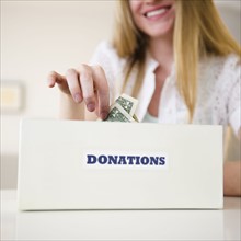 Woman putting money into donation box. 
Photo : Jamie Grill