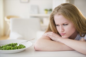 Woman leaning on table looking on green peas. 
Photo: Jamie Grill