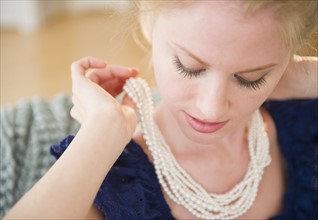 Woman putting on pearl necklace. 
Photo: Jamie Grill