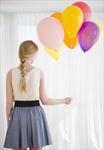 Woman holding bunch of colorful balloons. 
Photo: Jamie Grill