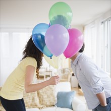 Couple kissing behind bunch of colorful balloons. 
Photo : Jamie Grill