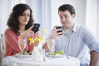 Couple having dinner and text messaging . 
Photo : Jamie Grill