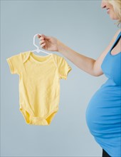 Pregnant woman holding onesie. 
Photo: Jamie Grill