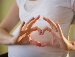 Pregnant woman making heart shape with hands. 
Photo : Jamie Grill