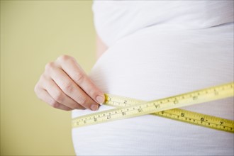 Pregnant woman measuring belly with tape measure. 
Photo : Jamie Grill