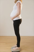 pregnant woman standing on weight scale. 
Photo : Jamie Grill