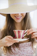 Woman wearing sun hat drinking tea. 
Photo : Jamie Grill