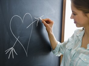Woman writing heart on blackboard. 
Photo: Jamie Grill