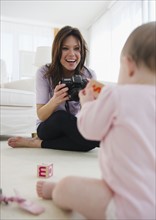 Mother photographing baby daughter (6-11 months). 
Photo : Jamie Grill