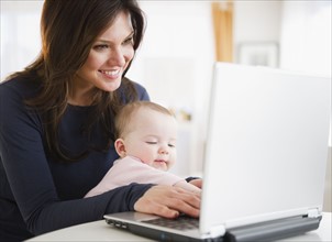 Mother with baby daughter (6-11 months) using laptop. 
Photo: Jamie Grill