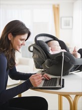 Mother with baby daughter (6-11 months) doing internet shopping. 
Photo : Jamie Grill