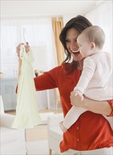 Mother with baby daughter (6-11 months) holding dress. 
Photo : Jamie Grill
