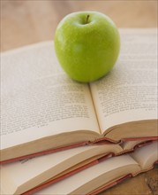 Close up of apple on open books, studio shot. 
Photo: Daniel Grill