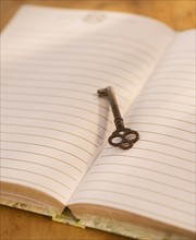 Close up of open notebook with key, studio shot. 
Photo : Daniel Grill