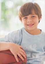 Portrait of smiling boy (10-11 years) with basketball ball. 
Photo : Daniel Grill