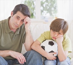 Father and son (10-11 years) watching football match with sadness. 
Photo: Daniel Grill