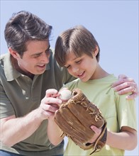 Father teaching son (10-11 years) how to play baseball. 
Photo : Daniel Grill