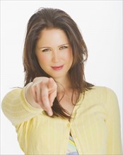 Portrait of smiling young woman pointing with finger, studio shot. 
Photo: Daniel Grill