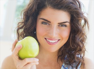 Portrait of smiling woman holding apple. 
Photo : Daniel Grill