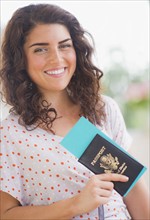 Portrait of smiling woman with passport. 
Photo: Daniel Grill