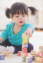 Portrait of baby girl (12-17 months) playing alphabet blocks. 
Photo : Daniel Grill