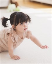 Portrait of baby girl (12-17 months) crawling on carpet. 
Photo : Daniel Grill