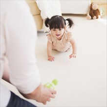 Father encouraging baby daughter (12-17 months) to crawl. 
Photo: Daniel Grill