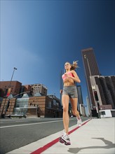 USA, California, Los Angeles, Young woman running on city street.