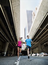 USA, California, Los Angeles, Young man and young woman running on city street. 
Photo: Erik