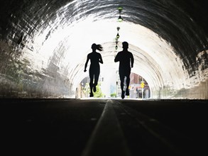 USA, California, Los Angeles, Man and woman running in tunnel.