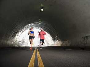 USA, California, Los Angeles, Young man and young woman running in tunnel. 
Photo: Erik Isakson