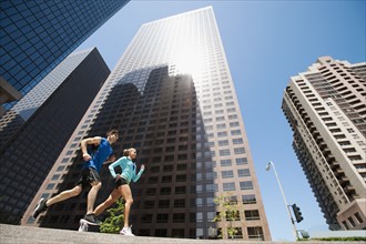 USA, California, Los Angeles, Young man and young woman running in city.