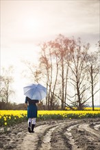 USA, Washington, Skagit Valley, Woman with umbrella on country road. 
Photo: Take A Pix Media