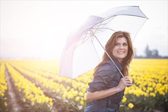 USA, Washington, Skagit Valley, Woman with umbrella against daffodil field. 
Photo : Take A Pix