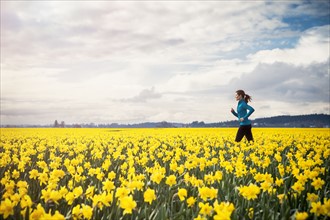 USA, Washington, Skagit Valley, Woman running through daffodil field. 
Photo : Take A Pix Media