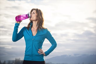 Woman drinking water after run. 
Photo : Take A Pix Media