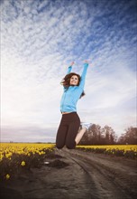 USA, Washington, Skagit Valley, Woman in blue tracksuit jumping in air. 
Photo: Take A Pix Media